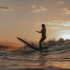 Suferin auf Surfboard, Meer im Vordergrund, Sonnenuntergangsstimmung